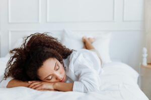 Photo by Thirdman : https://www.pexels.com/photo/photo-of-woman-lying-on-bed-7218828/ Alt-text: woman sleeping on her stomach, positional therapy