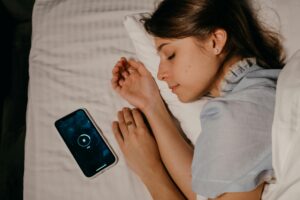 Photo by Polina ⠀: https://www.pexels.com/photo/phone-beside-an-asleep-woman-6541078/ woman sleeping next to her phone