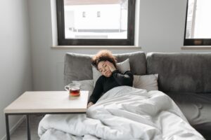 https://www.pexels.com/photo/woman-resting-6753226/ Woman on the couch rubbing her head with a cup of tea beside her